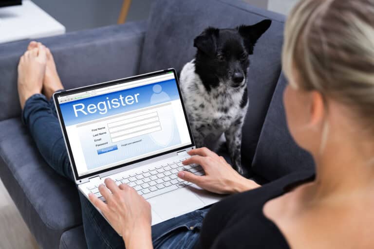 ESA registration, emotional support animal registration. A person sitting on the couch with a laptop on their legs and a medium sized dog sitting next to them