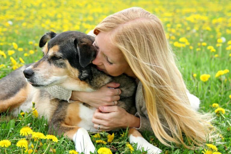 A Girl Laying Outside In The Grass Hugging Dog