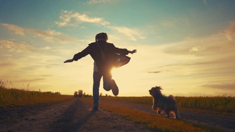 Teenage girl running with dog in the park