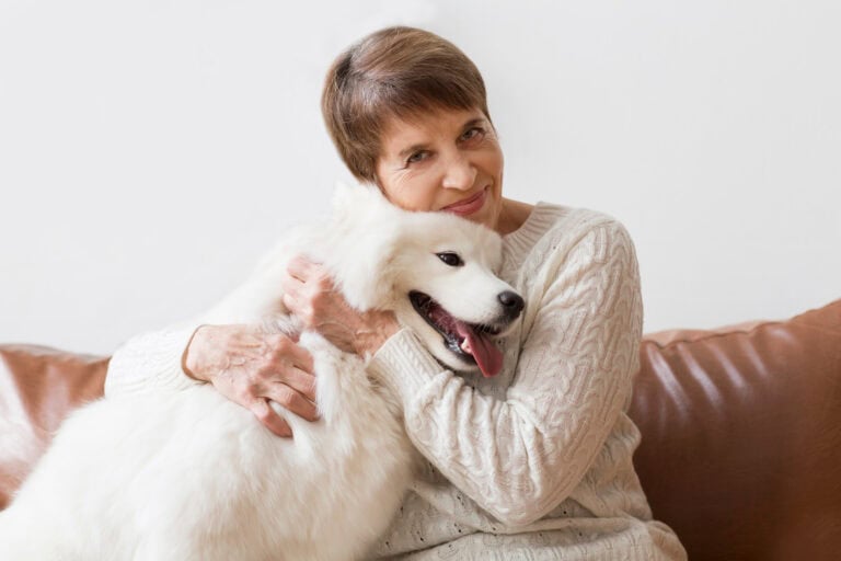 Senior woman hugging dog sitting on sofa