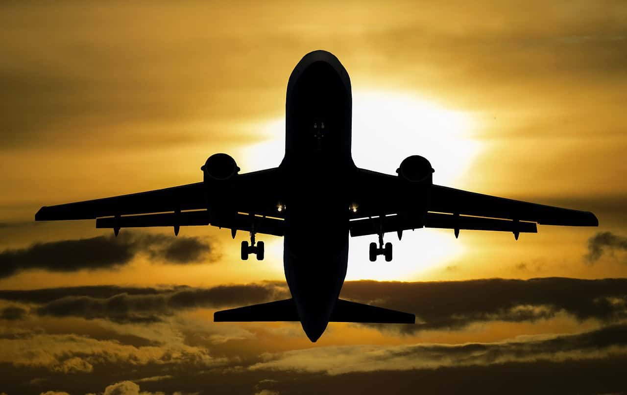 Airplane silhouette flying against a vibrant sunset sky