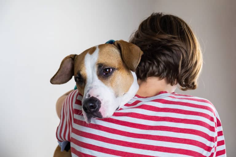 Woman with a dog on her shoulder, viewed from behind.