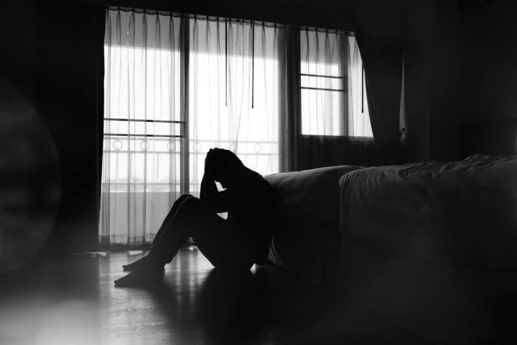 depressed man’s silhouette seated by the bed.