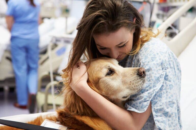 Woman in hospital hugging dog